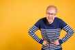 © sorapop - Portrait Asian old man with glasses holds hands on abdomen he stomach ache studio shot isolated yellow background, senior man pensioner feeling pain abdominal pain, hepatitis painful