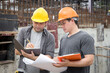 © skarie - Team of construction workers discussing project details with blueprint in construction site.