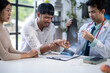 © Wasana - A doctor is examining a patient's hand and a woman is sitting behind him