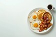 © Mamstock - A top down view of a full American breakfast on a white background with plenty of space for additional images The breakfast includes sunny side up fried eggs crispy bacon hash browns fluffy pancakes