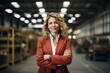 © Markus Schröder - Portrait of a cheerful woman in her 40s dressed in a stylish blazer isolated in bustling factory floor