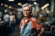© Markus Schröder - Portrait of a jovial woman in her 80s dressed in a casual t-shirt isolated on bustling factory floor