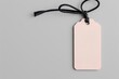 © Dominika - Elegant pink colored tag mockup with black string on grey background in a flat lay top view at high resolution, leaving empty space for text or product.