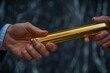 © Yuliia - close-up shot of a hand passing a golden relay baton to a businesswoman, symbolizing teamwork and connection in the business world.