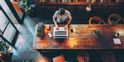 Sticker - A man is sitting at a wooden table with a laptop in front of him