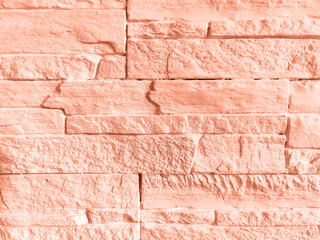 Abstract geometric background of wall lined with coral color decorative stone tiles. Close-up. Copy space.