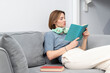 © Vitaliy - Attractive girl in headphones reading book at home. Audiobook and home education concept