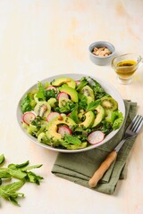 Wall Mural - Green salad of cabbage Kale and salad Romen with kiwi, petiole celery and avocado in a gray bowl on a light concrete background