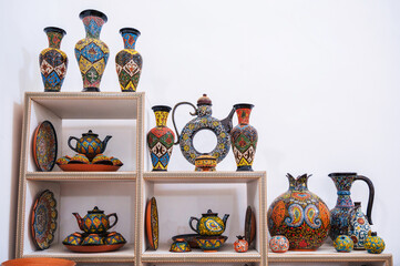 Wall Mural - Asian Uzbek handmade ceramic vases and dishes with hand-painted Asian colorful patterns on shelves in the oriental souvenir tableware store