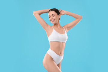 Wall Mural - Diet and weight loss concept. Beautiful young woman with slim body against light blue background