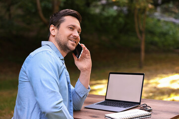 Canvas Print - Smiling freelancer talking on smartphone outdoors. Remote job