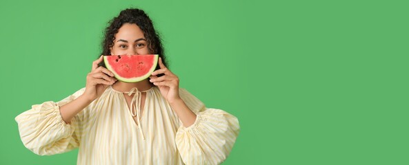 Wall Mural - Happy young African-American woman with slice of fresh watermelon on green background with space for text