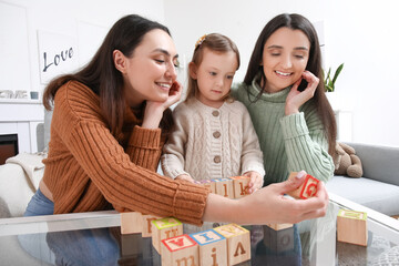 Sticker - Young lesbian couple and adopted little girl playing with cubes at home