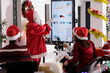 © DC Studio - Trainer disguised in Santa Claus doing special occasion business meeting before Christmas holiday season. Employees in xmas clothing discussing financial quarterly results in festive decorated office
