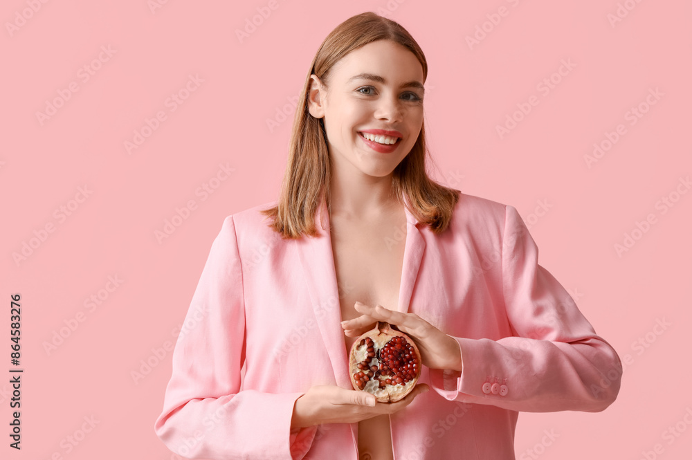 Young woman with pomegranate on pink background