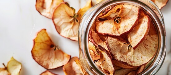 Close-up of organic apple chips in a glass jar on a white background with space for text, featuring a homemade crispy appearance and sun-dried texture. Copy space image