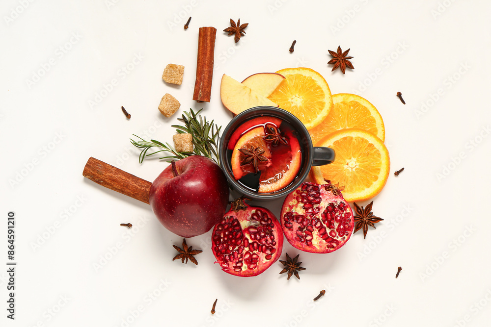 Cup of hot mulled wine and different ingredients on white background