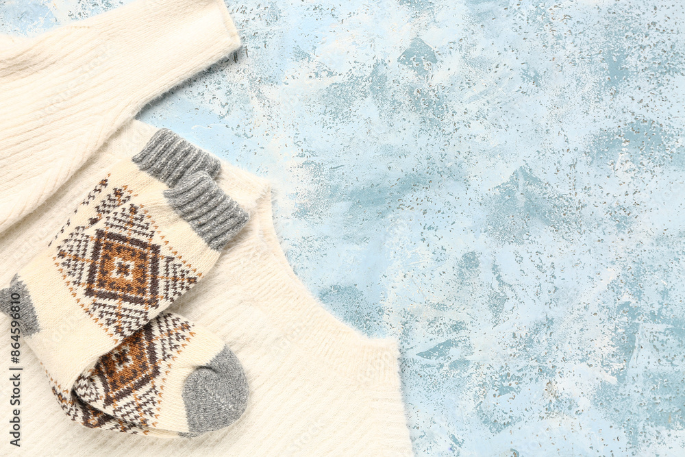 Warm socks and sweater on blue background