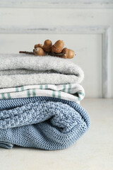Wall Mural - Stack of new stylish sweaters and acorns on light background