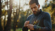 © solom - A man in sportswear is setting up his smartwatch before an outdoor run, focusing on the watch's features and heart rate monitor display with trees and sunlight blurred behind him.