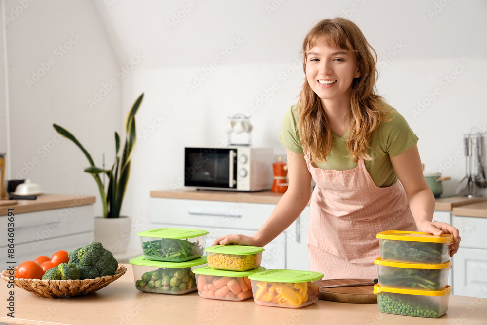 Beautiful young woman and plastic containers with vegetables for freezing on table in kitchen
