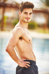 A man with a muscular chest stands in front of a pool, athletic fit people