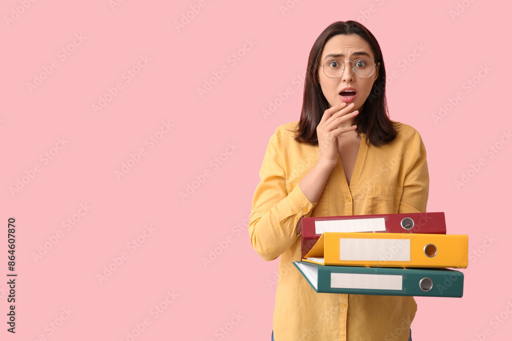 Shocked young businesswoman with document folders on pink background