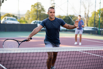 Wall Mural - Man in t-shirt playing tennis on court. Racket sport training outdoors.