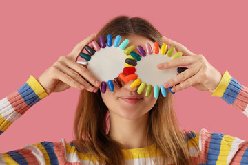 Wall Mural - Young woman with nail polishes palettes on pink background