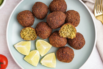 Wall Mural - Plate with delicious falafel balls and lime on light background, closeup