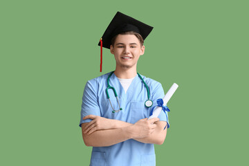 Wall Mural - Happy male medical graduate with diploma and stethoscope on green background