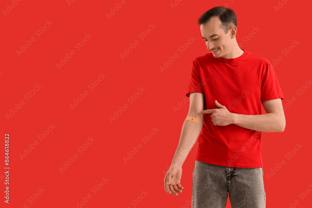 Male blood donor pointing at applied patch on red background