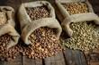 © At My Hat - Three bags of different colored beans are piled on a wooden table. The beans are of different colors and sizes, and they are all piled together in a pile