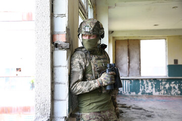 Wall Mural - Military mission. Soldier in uniform with binoculars inside abandoned building