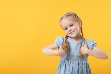 Poster - Cute little girl showing thumbs up on orange background, space for text