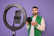 © New Africa - Technology blogger reviewing camera and recording video with smartphone and ring lamp on purple background