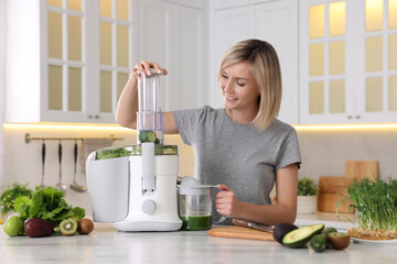 Poster - Smiling woman with fresh products using juicer at white marble table in kitchen