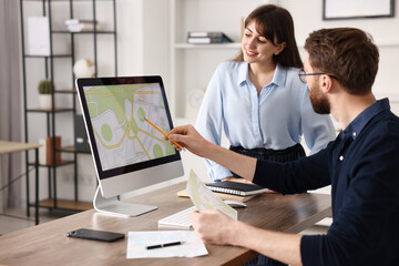 cartographers working with cadastral map on computer at table in office