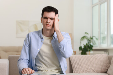 Poster - Man suffering from headache on sofa at home