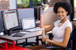 © Wavebreak Media - Smiling businesswoman sitting at desk with laptop and financial charts on screen