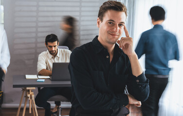 Confidence and happy smiling businessman portrait with blur motion background of his colleague and business team working in office. Office worker teamwork and positive workplace concept. Prudent