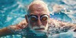 © vefimov - A man in a swimming pool wearing goggles and a bathing suit. He is looking at the camera
