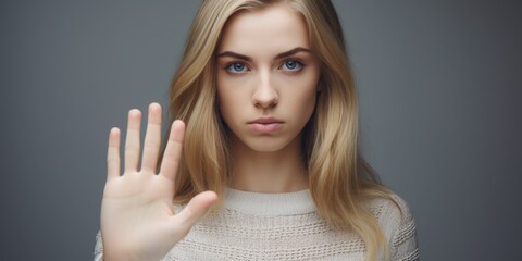 A woman with blonde hair and blue eyes is holding up her hand to stop something. Concept of urgency and importance, as if the woman is trying to prevent something bad from happening
