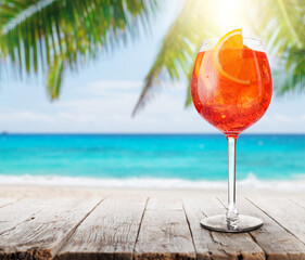 Poster - Glass of Aperol Spritz on a table with a stunning sea and beach background