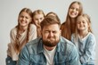 © gearstd - A man in a denim jacket is making a funny face in the foreground, surrounded by a group of young women smiling and laughing, capturing a lighthearted and fun moment.