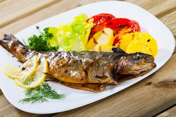 Sticker - Picture of tasty baked whole trout with potatoes, greens and tomatoes on white plate