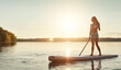© ReeseArcurs/peopleimages.com - River, sunset and woman on paddle board with sunshine, water sport and vacation on lake for tourism. Exercise, summer or holiday in Florida for female person, swimsuit or travel fitness for adventure