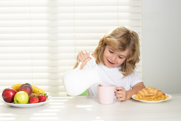 Wall Mural - Pretten child pouring whole cows milk. Kid preteen boy in the kitchen at the table eating vegetable and fruits during the dinner lunch. Healthy food, vegetable dish for children.