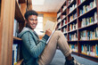 © NonVig/peopleimages.com - University student, man and portrait with writing in library for studying, scholarship and reading a book for exam info. Education, person and happy with notebook for research and knowledge on floor
