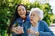 © Halfpoint - Female caregiver and senior woman in wheelchair holding dandelion, picking wild flowers. Nurse and elderly woman enjoying a warm day in nursing home, public park.
